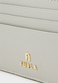 Portafoglio in pelle grigia con più slot per carte e il logo dorato "A FURLA" impresso sul fronte. Superficie testurizzata con cuciture discrete.