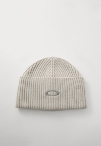 Jasnoszara, prążkowana czapka beanie z podwiniętym mankietem i małym tłoczonym logo z przodu. Miękka tekstura z pionowymi liniami.