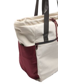 Torba tote w beżowym kolorze i bordowym panelu bocznym. Wykonana z teksturowanej tkaniny, wyposażona w dwie mocne czarne uchwyty oraz zasuwaną kieszeń.