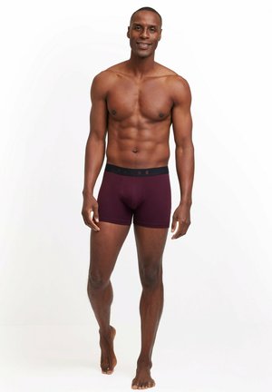 Burgundy boxer shorts with black waistband featuring the brand "FALKE" in a repeated pattern; smooth texture and fitted design.