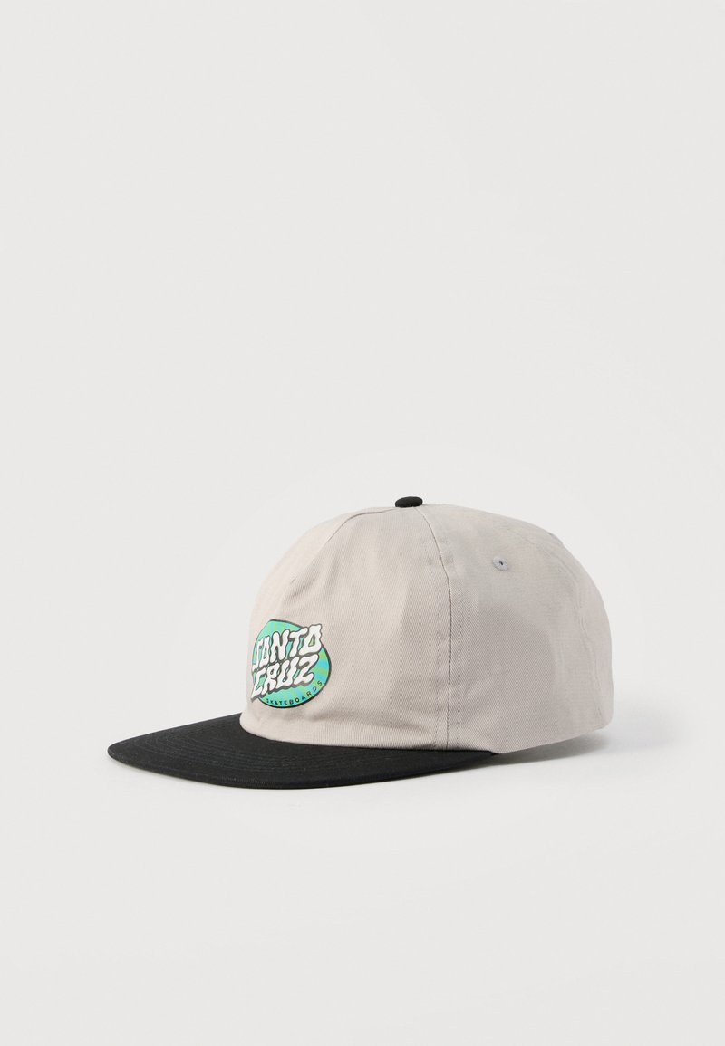 Καπέλο με επίπεδη κορυφή σε μπεζ και μαύρο χρώμα, με πράσινο και λευκό λογότυπο "Santa Cruz Skateboards" στο μπροστινό πάνελ, τοποθετημένο πάνω σε λευκή επιφάνεια.