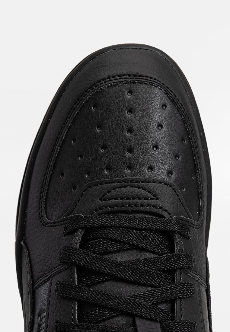 Czarne skórzane buty sportowe z perforowanym czubkiem, płaskimi czarnymi sznurowadłami i gładką fakturą. Minimalistyczny design bez wyraźnych akcentów.