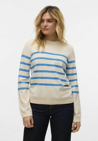 Crème sweater met blauwe horizontale strepen, ronde halslijn en lange mouwen. Zachte textuur en slim-fit ontwerp, gedragen met donkere jeans.