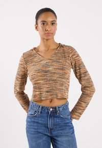 Top a maniche lunghe, croppato, in tessuto arancione e marrone testurizzato con scollatura a V. Abbinato a jeans di denim a vita alta.