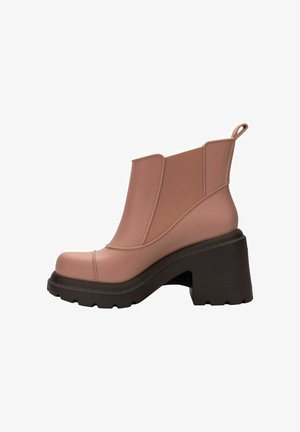 Różowy gumowy botek za kostkę z masywnym czarnym obcasem i elastycznymi panelami bocznymi. Gładka faktura, okrągły nos oraz tylna pętelka ułatwiająca zakładanie.