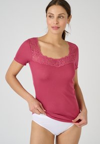 Haut à manches courtes framboise avec une texture côtelée et une finition en dentelle florale le long du décolleté carré, associé à des sous-vêtements blancs.