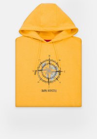 Żółta bluza z kapturem, ozdobiona wzorem kompasu i napisem "TRAVEL WITH STYLE" w czarnym kolorze, charakteryzująca się miękką fakturą i luźnym krojem.