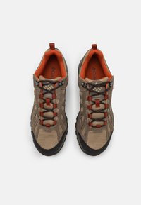 Beige hiking shoes with brown rubber soles. Features orange accents, black lacing, and mesh panels for ventilation. Logo visible on the insole.