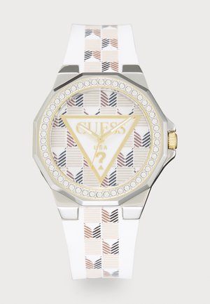 Relógio com bracelete em silicone branco, caixa prateada octogonal, mostrador com padrão, detalhes em dourado e bezel em cristal. Apresenta o logótipo da marca e design triangular.