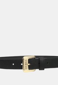 Schwarzer Lederbalt mit strukturiertem Finish, ausgestattet mit einer goldfarbigen Metallschnalle, die mit dem Markennamen "GUESS" geprägt ist. Verstellbare Passform mit Löchern.