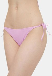 Costume da bagno rosa con un design a vita bassa, lacci laterali regolabili e texture del tessuto liscia. Assente qualsiasi motivo o dettaglio decorativo.
