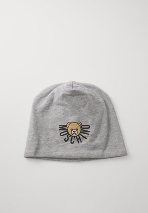 Pilkas verpimo kepurė, pagaminta iš minkštos medžiagos, su meškos piešiniu ir žodžiu "Moschino" juodomis raidėmis, esančiomis centre priekyje.