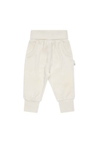Pantaloni della tuta color crema in morbido tessuto, con cintura elasticizzata, polsini a coste e due tasche frontali. Design minimalista, senza motivi.