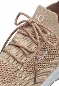 Sneaker beige in maglia con lacci coordinati legati a fiocco, con lati in rete testurizzata e suola bianca.