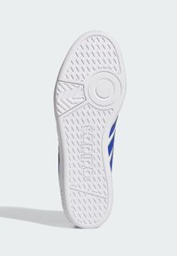 Suela de zapato de goma blanca con un dibujo en relieve, con una silueta superior en azul y negro y la marca "adidas".