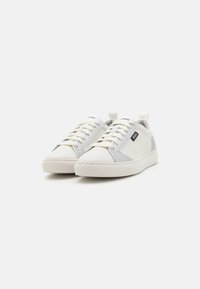 Białe skórzane sneakersy z szarymi akcentami, okrągły czubek, płaska gumowa podeszwa, teksturowane wykończenie oraz detal z logo na języku.