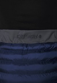 Marinblå puffjacka med en slät textur, försedda med en grå panel högst upp och en präglad logotyp "Icepeak" nära halsringningen.