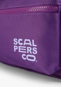 Bolsa de nailon púrpura con un bolsillo con cremallera y texto de logo blanco. La superficie tiene un patrón texturizado, lo que mejora la durabilidad y el estilo.