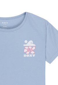Lys blå organisk bomulds t-shirt med et hvidt bølgemotiv og en lyserød blomst med "ROXY" tekst nedenfor. Klassisk rund halsudskæring og korte ærmer.