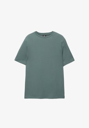 Lyhythihainen t-paita hillityn vihreänä, pehmeästä puuvillakankaasta, jossa on pyöreä kaula-aukko ja rento istuvuus ilman koristeita.