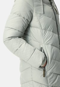 Light green puffer jacket with horizontal quilted pattern, zippered side pocket, and drawstring hood. Soft, smooth texture.