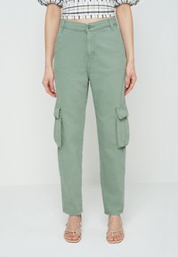 Cargo-byxor i ljusgrön bomull, slim fit, med två sidofickor med lock, knappstängning och bältesöglor.