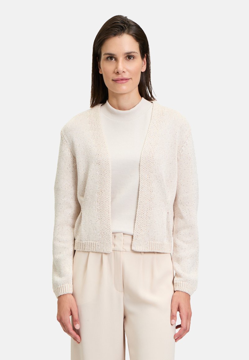 Light beige knitted cardigan with a relaxed fit, featuring a V-neck, ribbed cuffs, and open front. Worn over a cream turtleneck.