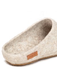 Pantofola in felt beige con una texture morbida, forma arrotondata e etichetta in pelle con la scritta "magicfelt". Presenta una suola piatta e antiscivolo.