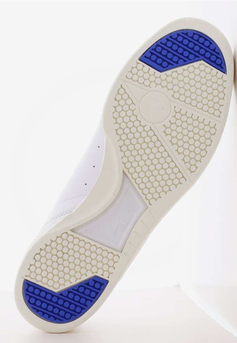 Weiße Sneaker-Sohle mit einer strukturierten GummOberfläche, blauen und weißen Akzenten, hexagonalen Mustern und einem ausgeprägten Traktionsdesign.