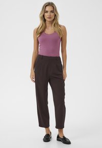 Fitted purple ribbed tank top with scalloped neckline paired with high-waisted dark brown trousers featuring front pleats and rolled hem.