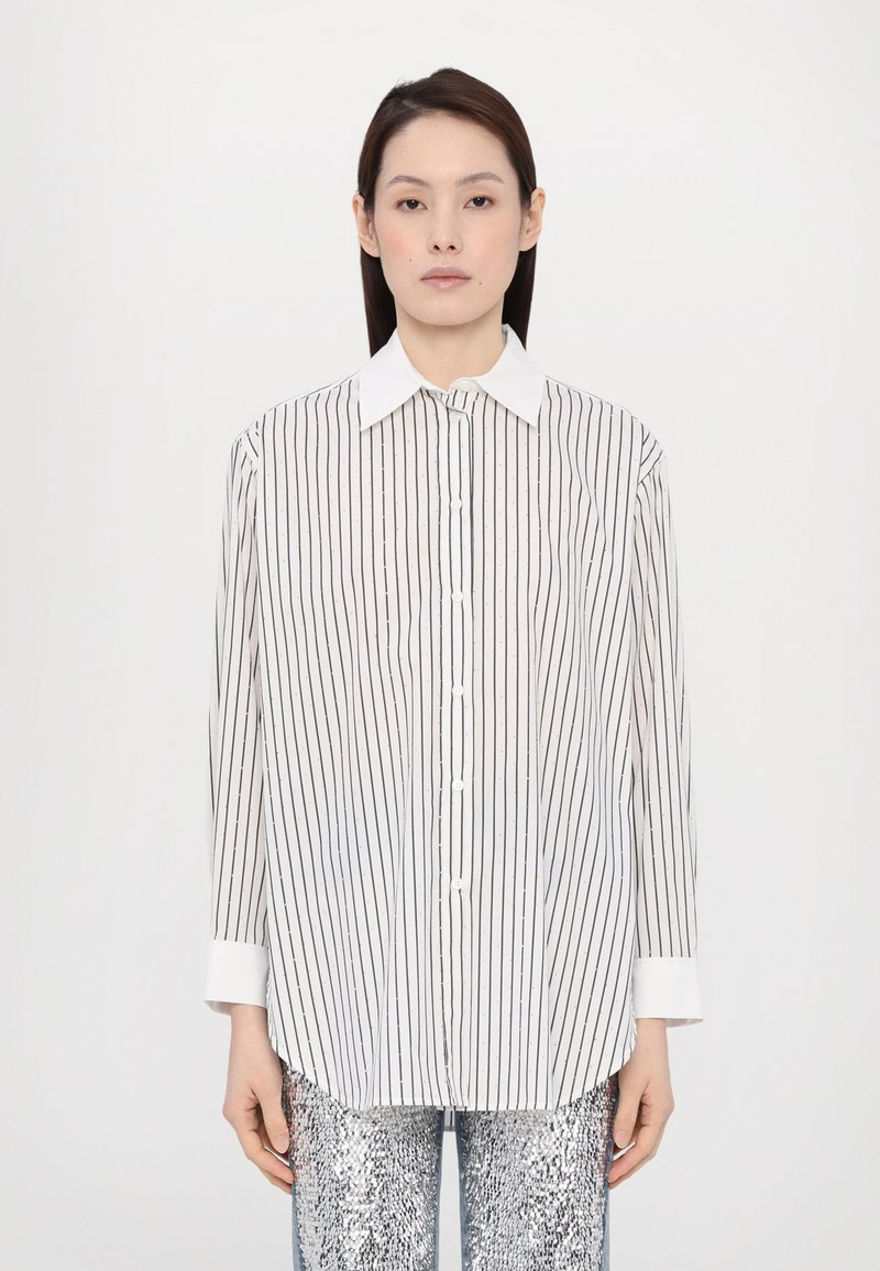 Witte blouse met dunne zwarte verticale strepen, voorzien van een klassiek kraag en lange mouwen, gecombineerd met glanzende zilveren paillettenbroek.