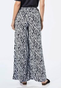 Wijd uitgesneden broek met een zwart-wit zebra-streep patroon, gemaakt van lichtgewicht stof, met een elastische tailleband en een relaxte pasvorm.