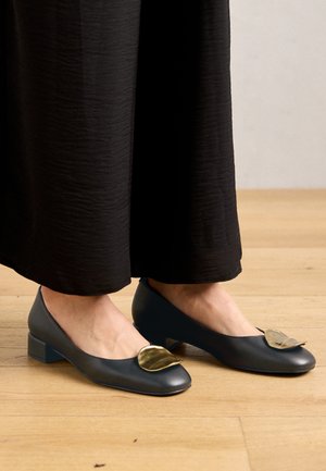 Chaussures plates bleu foncé avec un bout arrondi, ornées d'un accent en feuille d'or. La surface texturée et le talon bas offrent une meilleure stabilité.