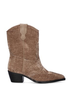 Botas de vaquero de ante marrón con puntas afiladas y tachuelas decorativas de bronce en la parte inferior. Presentan un tacón negro bajo y detalles de costura.