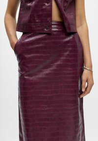 Bordeaux leren rok met een krokodillenstructuur, met een hoge taille en zijkanten zakken, gecombineerd met een bijpassend cropped vest.