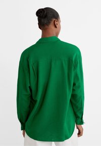 Groene button-up shirt gemaakt van lichtgewicht stof met lange mouwen en een relaxte pasvorm, met een kraag en een rechte onderrand.