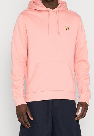 Sudadera melocotón con un bolsillo canguro, capucha ajustable con cordón, y un pequeño logo amarillo en el pecho. Tejido suave de mezcla de algodón.