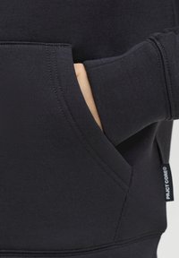 Sweat à capuche noir avec une poche kangourou à l'avant. Confectionné dans un tissu doux, avec des poignets côtelés et une étiquette sur le côté. Texture lisse et coupe ajustée.