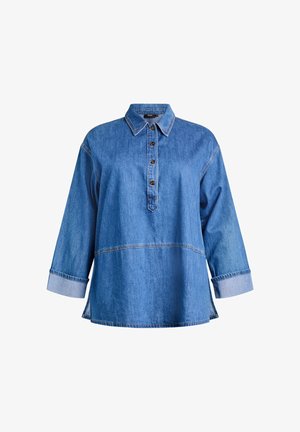 Denimskjorte i mediumblå med knappelukning foran, spids krave og lange ærmer. Har kontrastfarvede manchetter og syningdetaljer.