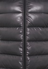 Black padded jacket featuring a quilted texture with horizontal stitching, a central zipper closure, and a smooth, glossy surface.