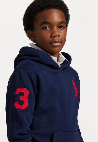 Jūras spēku kapuce no kokvilnas maisījuma ar kangaroo kabatu, ar sarkanu izšuvumu numuru "3" uz piedurknes un sarkanu polo logotipu uz krūšu.