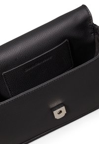 Borsa a mano in pelle nera con superficie testurizzata, dotata di una chiusura quadrata metallica e una tasca interna per l'organizzazione.