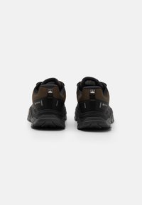 Brown and black trail sneakers with a textured surface, cushioned heel, and reflective accents; features a Gore-Tex logo for water resistance.