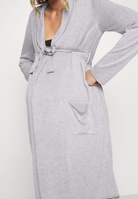 Grauer Bademantel aus weichem Stoff, mit tailliertem Gürtel, langen Ärmeln, zwei Seitentaschen und einem Schalkragen-Design.