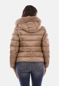 Giacca imbottita marrone chiaro con cappuccio rifinito in pelliccia, caratterizzata da un design trapuntato orizzontale, texture lucida e silhouette aderente.