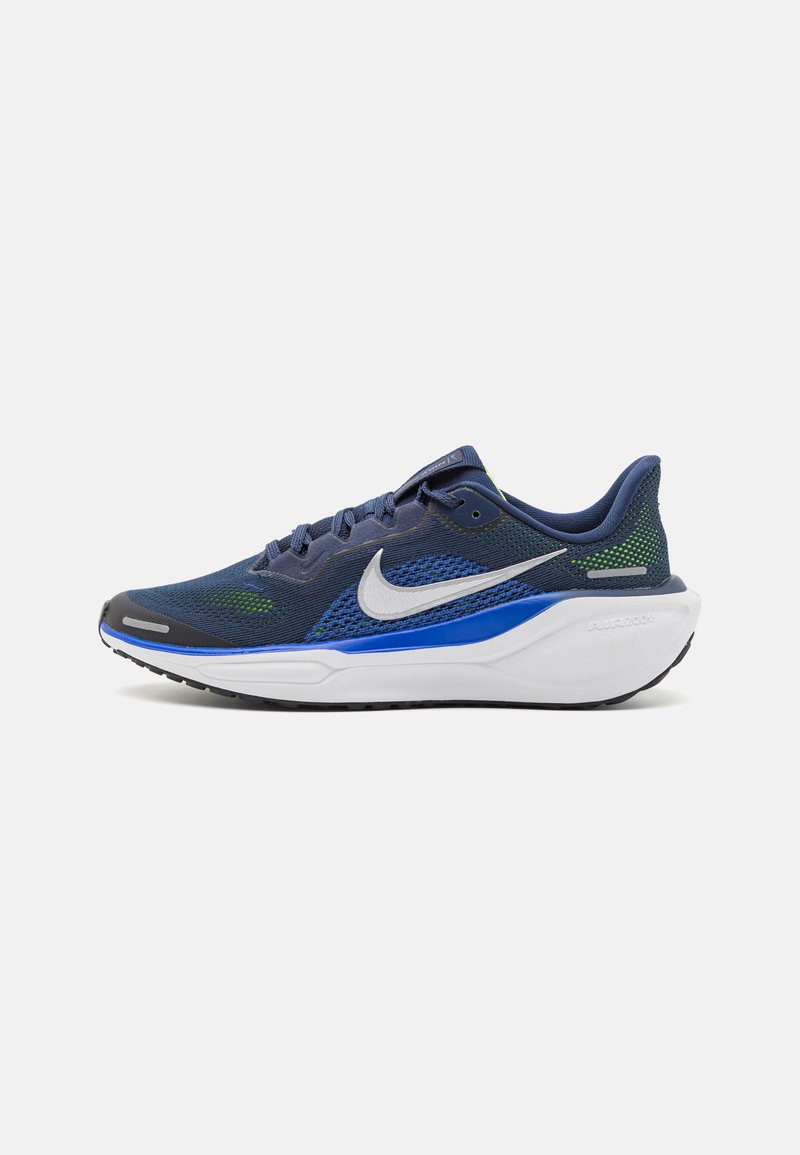 Chaussure de course Nike, avec une tige en maille bleu foncé et des accents verts, une semelle intermédiaire blanche et une semelle extérieure noire. Design à lacets avec un détail de logo.
