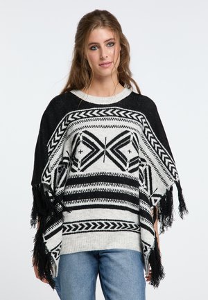 Poncho a righe in bianco e nero con dettagli a frange, caratterizzato da un design geometrico e un ampio scollo, realizzato in un morbido materiale lavorato a maglia.