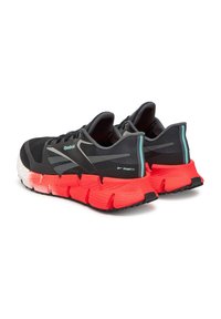 Čierne tenisky Reebok so sieťovaným vrchom, s textúrovanou podrážkou v červenej a bielej farbe, zadnými pútkami a reflexnými akcentmi.