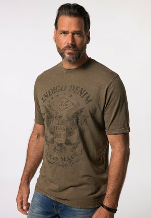 Camiseta de manga corta en verde oliva con un gráfico vintage de un águila y texto; cuello redondo, textura suave, tejido ligeramente desgastado.