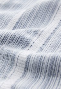 Katoenen stof met een zachte textuur, voorzien van smalle blauw-witte strepen en een geweven patroon. Glad, lichtgewicht en valt soepel.